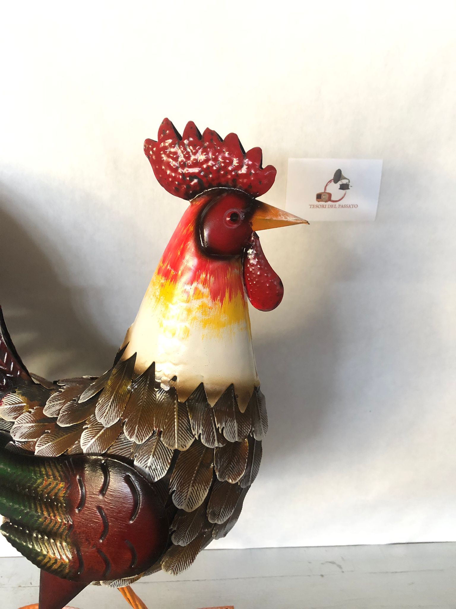 Gallo decorativo in metallo dipinto a mano, ideale per arredare giardino, terrazzo, balcone, portico o ambienti interni in stile rustico e country. Realizzato interamente in metallo con dettagli tridimensionali in rilievo, presenta una ricca lavorazione delle piume e una finitura anticata dai colori vivaci che dona carattere e originalità a qualsiasi spazio. La struttura autoportante garantisce stabilità e permette di posizionarlo facilmente senza necessità di supporti. Perfetto come complemento d'arredo pe