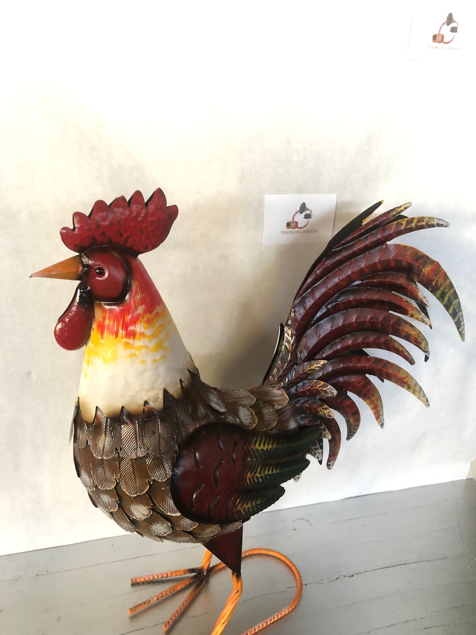 Gallo decorativo in metallo dipinto a mano, ideale per arredare giardino, terrazzo, balcone, portico o ambienti interni in stile rustico e country. Realizzato interamente in metallo con dettagli tridimensionali in rilievo, presenta una ricca lavorazione delle piume e una finitura anticata dai colori vivaci che dona carattere e originalità a qualsiasi spazio. La struttura autoportante garantisce stabilità e permette di posizionarlo facilmente senza necessità di supporti. Perfetto come complemento d'arredo pe