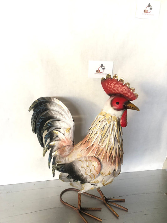 **Gallo decorativo in metallo dipinto a mano, ideale per arredare giardino, terrazzo, balcone, veranda o ambienti interni in stile rustico, country e shabby chic. Realizzato interamente in metallo con lavorazione tridimensionale delle piume, si distingue per la raffinata finitura nei toni del bianco, grigio, nero e oro anticato, impreziosita da cresta e bargigli rossi che donano un aspetto elegante e realistico. La struttura autoportante garantisce stabilità e consente di posizionarlo facilmente su qualsias