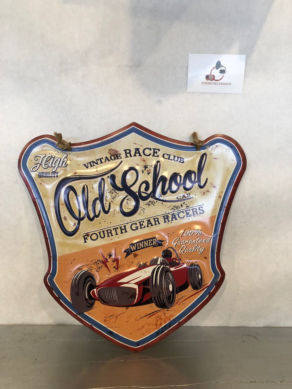 **Targa decorativa sagomata in metallo in stile vintage dedicata al mondo delle corse automobilistiche d'epoca. La grafica raffigura una classica auto da competizione con richiami ai Vintage Race Club e alle storiche gare automobilistiche, arricchita da una finitura effetto anticato e dettagli in rilievo che esaltano il fascino retrò. La particolare forma sagomata e la corda in juta inclusa permettono di appenderla facilmente, rendendola ideale per garage, officina, taverna, sala hobby, pub, bar, showroom e