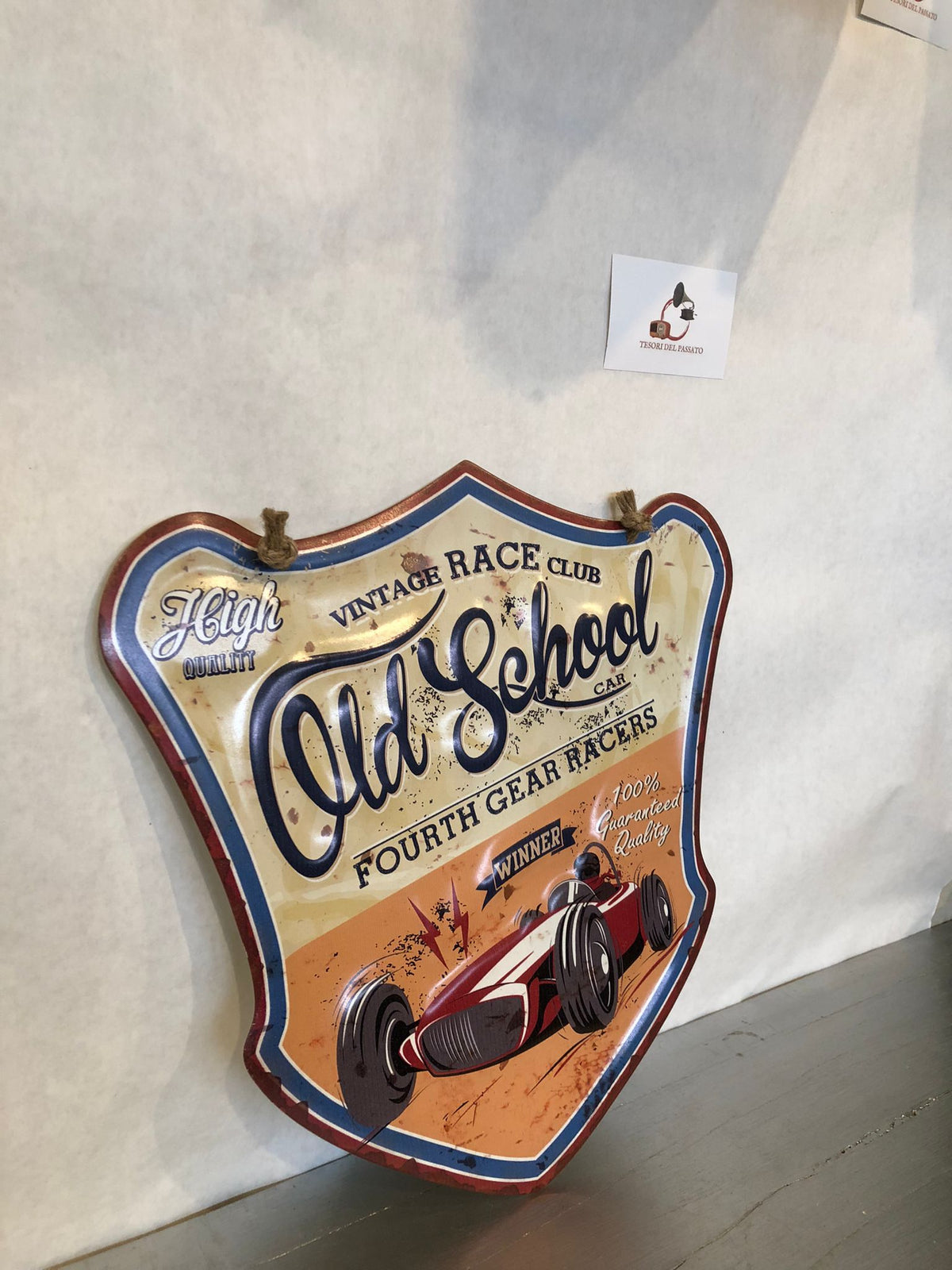 **Targa decorativa sagomata in metallo in stile vintage dedicata al mondo delle corse automobilistiche d'epoca. La grafica raffigura una classica auto da competizione con richiami ai Vintage Race Club e alle storiche gare automobilistiche, arricchita da una finitura effetto anticato e dettagli in rilievo che esaltano il fascino retrò. La particolare forma sagomata e la corda in juta inclusa permettono di appenderla facilmente, rendendola ideale per garage, officina, taverna, sala hobby, pub, bar, showroom e